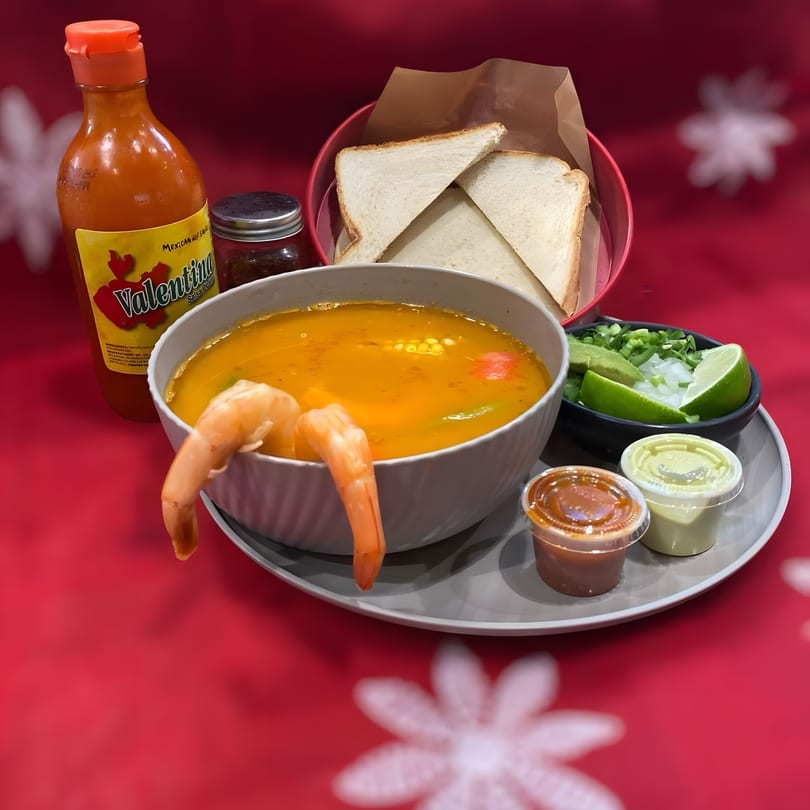 Shrimp soup with Valentina hot sauce, bread, and sides of avocado, lime, and onion.